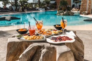 Enjoy a lavish poolside meal at a luxury resort in Ibiza, featuring tropical drinks and gourmet dishes.